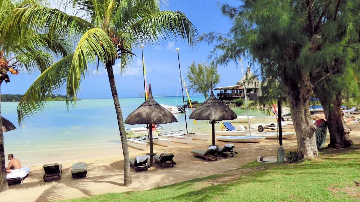 Tropischer Strand auf Mauritius mit Palmen, Sonnenliegen und kristallklarem Wasser