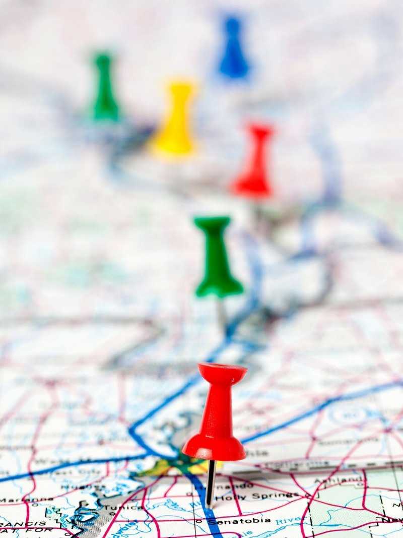 Reiseplanung mit markierten Zielen auf der Landkarte Nahaufnahme einer Landkarte mit farbigen Stecknadeln, die verschiedene Reiseziele markieren