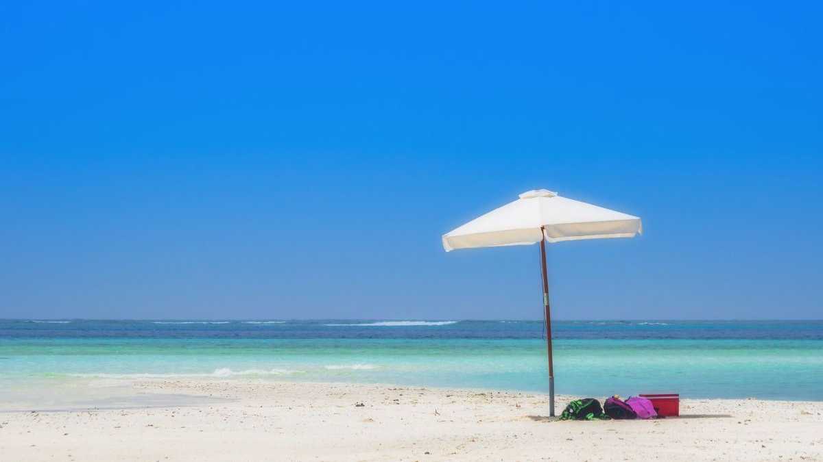 Weiße Sandbank auf den Malediven mit Sonnenschirm und türkisfarbenem Wasser im Hintergrund